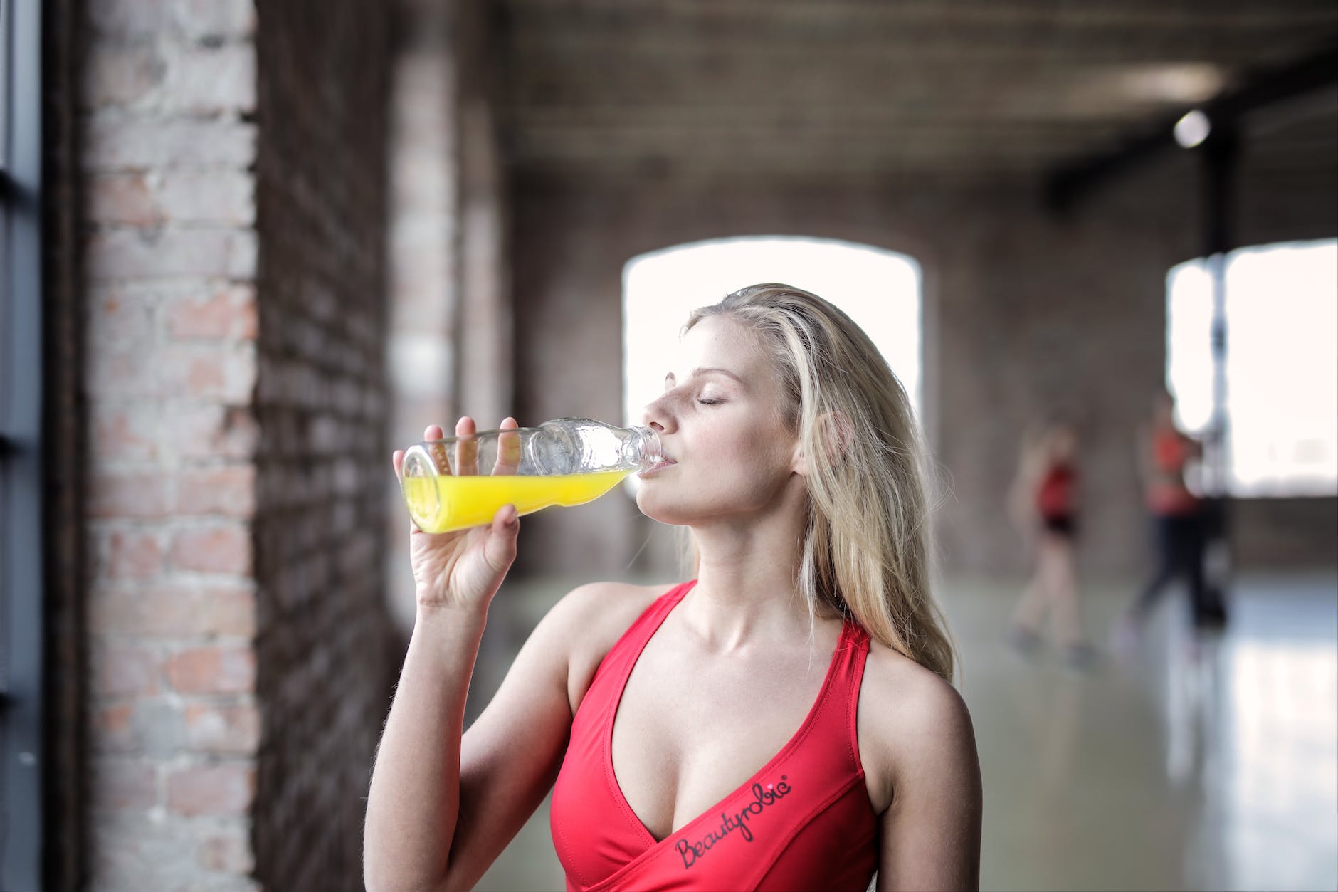 selective focus photography of woman in red tank top drinking