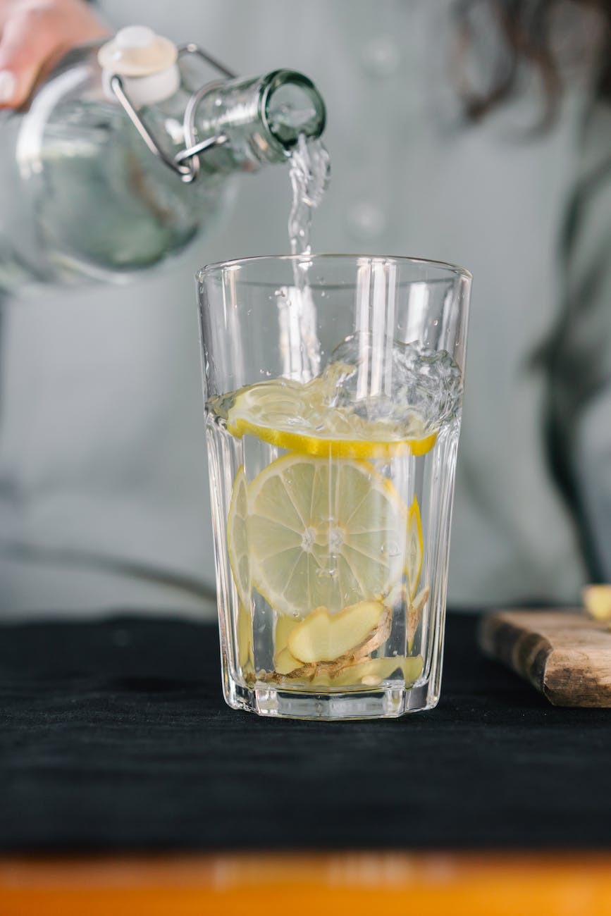 close up shot of a person pouring water on a glass with a lemon
